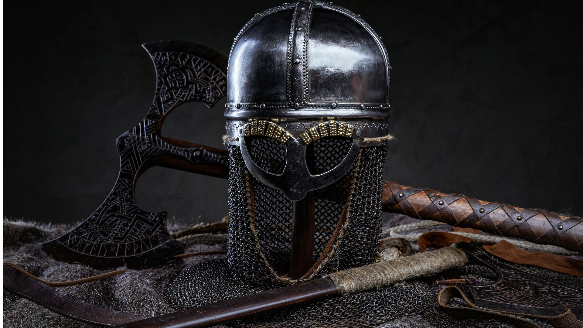 Casques et armes vikings, dont des haches, disposés sur une peau de bête